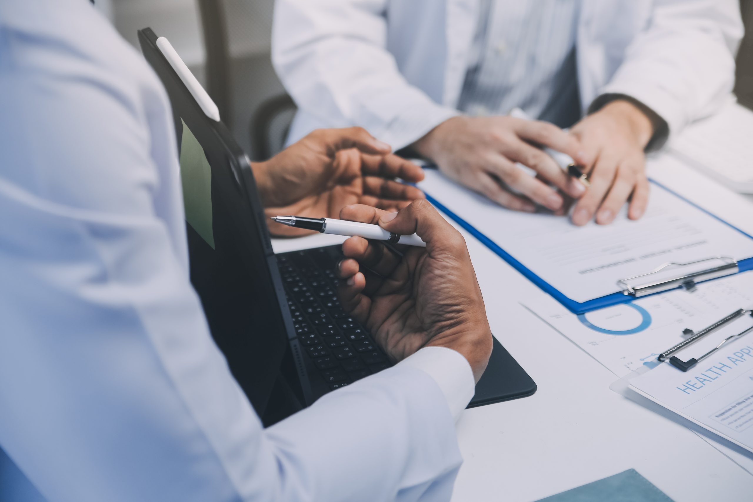 Meeting, tablet and team of doctors with collaboration for healthcare talk and telehealth app in office. Surgeon group, tech and medical discussion with website for hospital funding or sponsorship